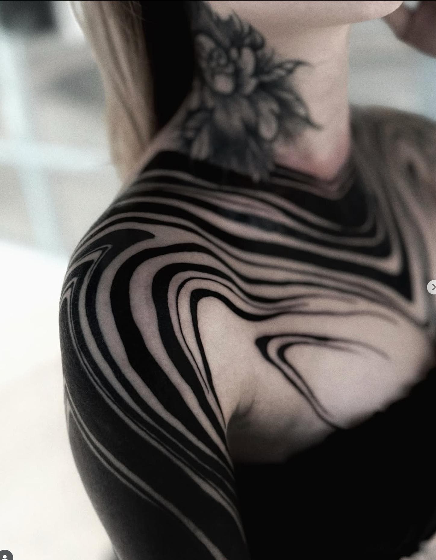 Solid black abstract design covering shoulder and neck