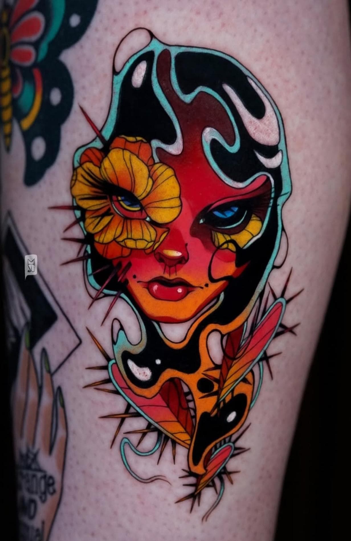 Colorful face and flower tattoo on thigh