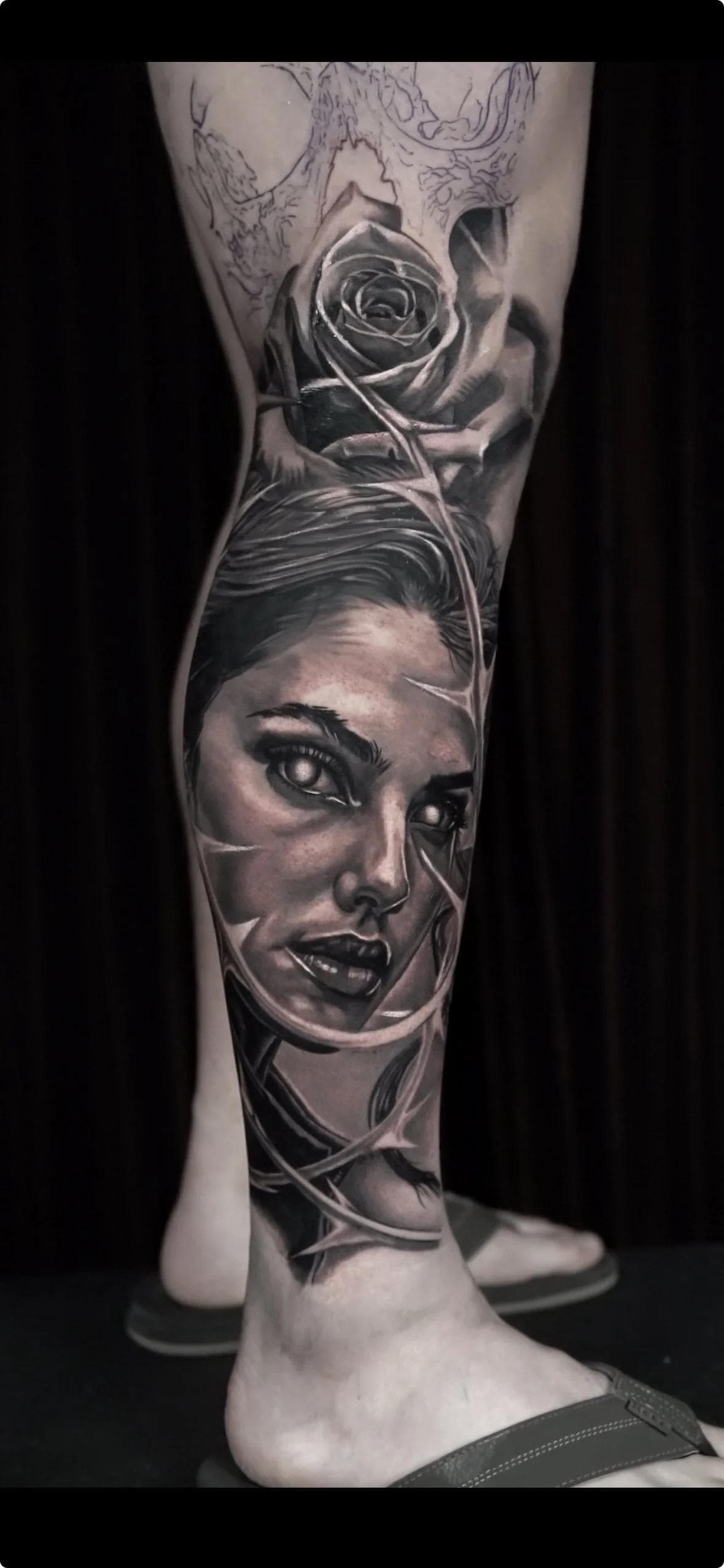 Black and grey realistic portrait and rose tattoo on calf