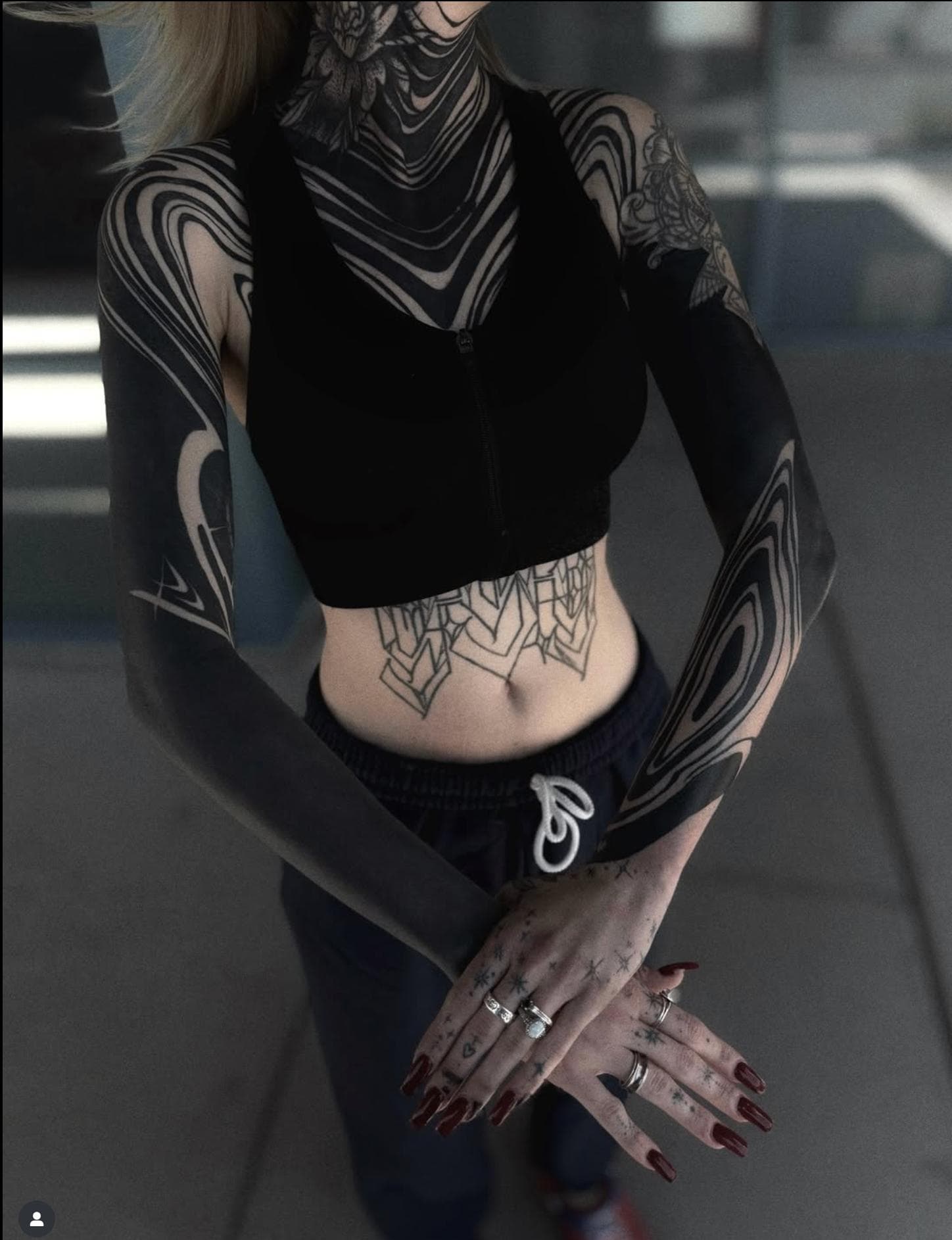 Blackwork tattoos with geometric patterns covering full arms and neck